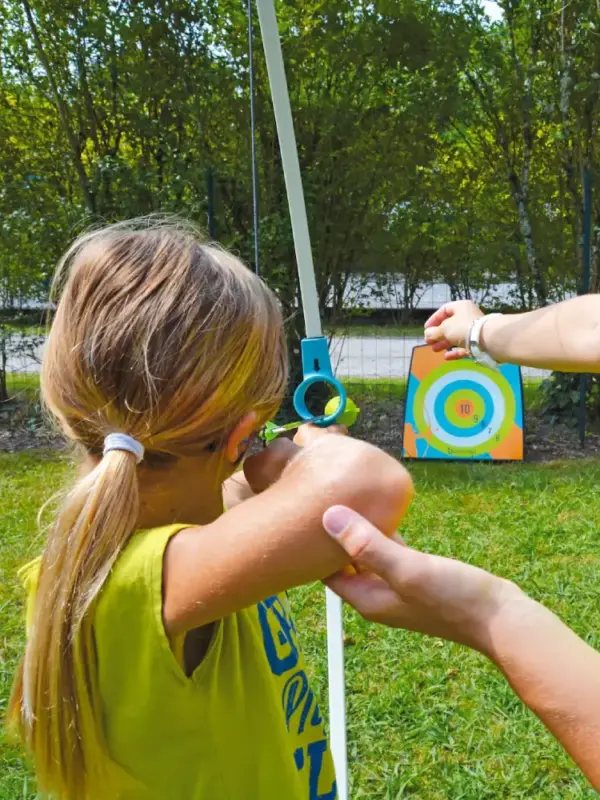 Enfant vise une cible avec un arc.