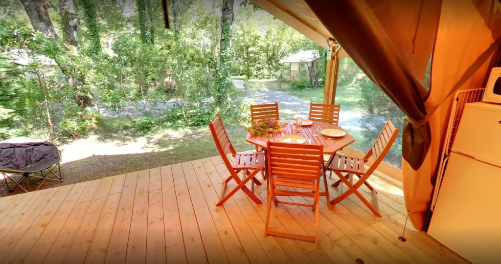 Terrasse en bois avec table et chaises extérieures.