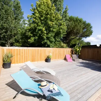 Chaises longues sur terrasse ensoleillée avec arbres.