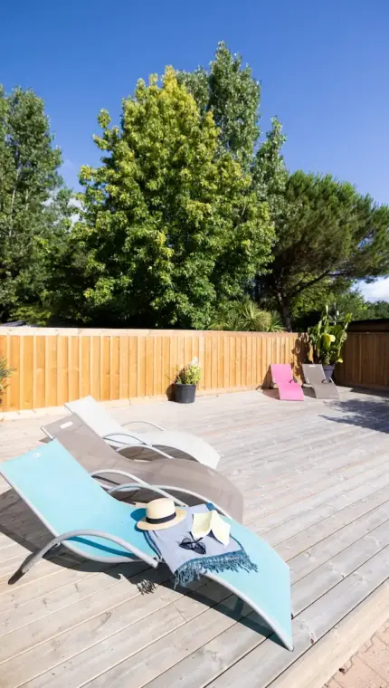 Chaises longues sur terrasse ensoleillée boisée.
