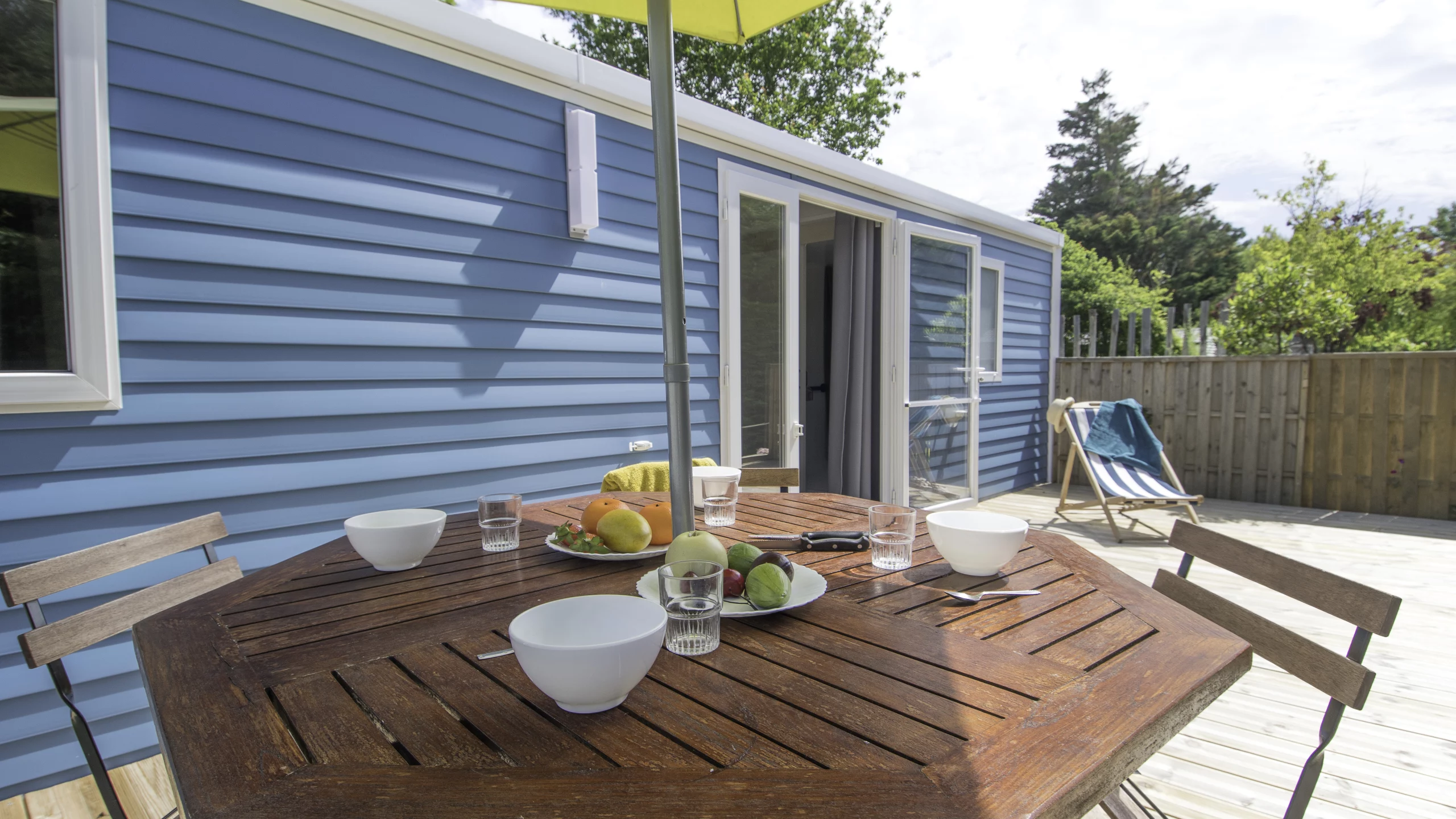 Terrasse ensoleillée avec table en bois et chaises.