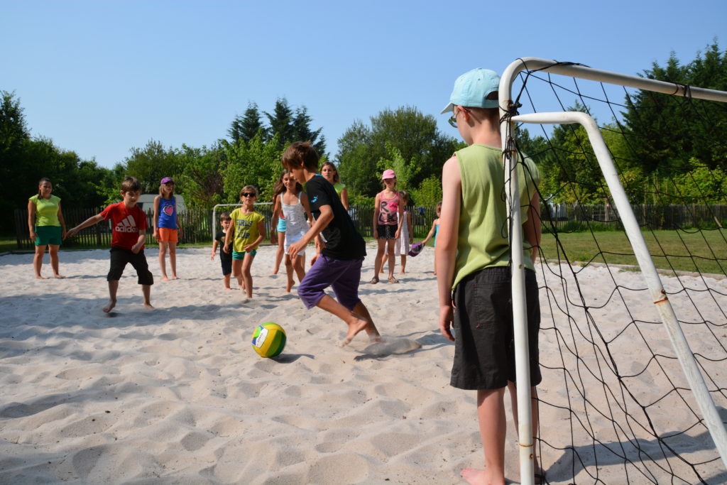Enfants jouant au foot sur du sable