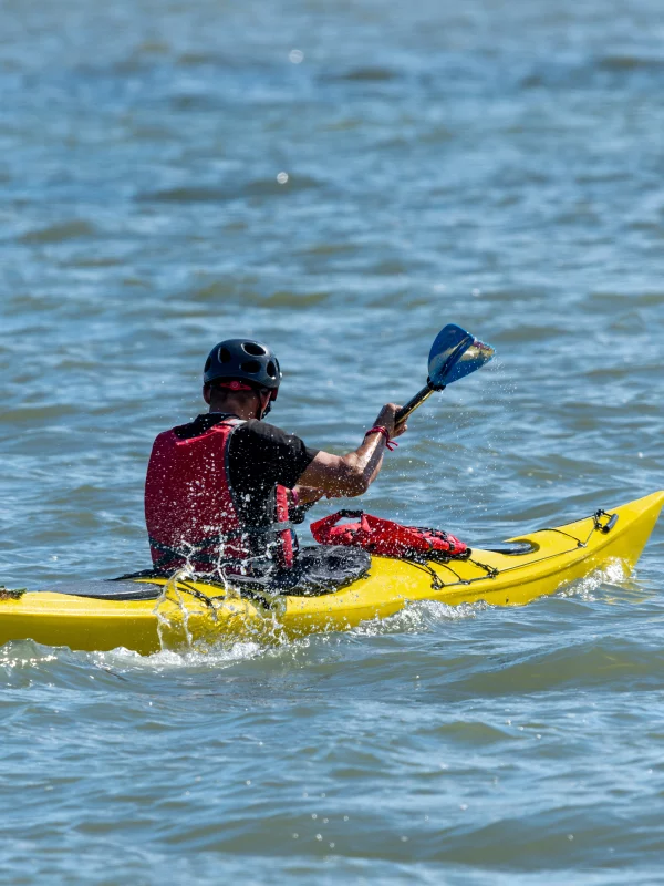 Homme pagayant en kayak jaune sur l'eau.