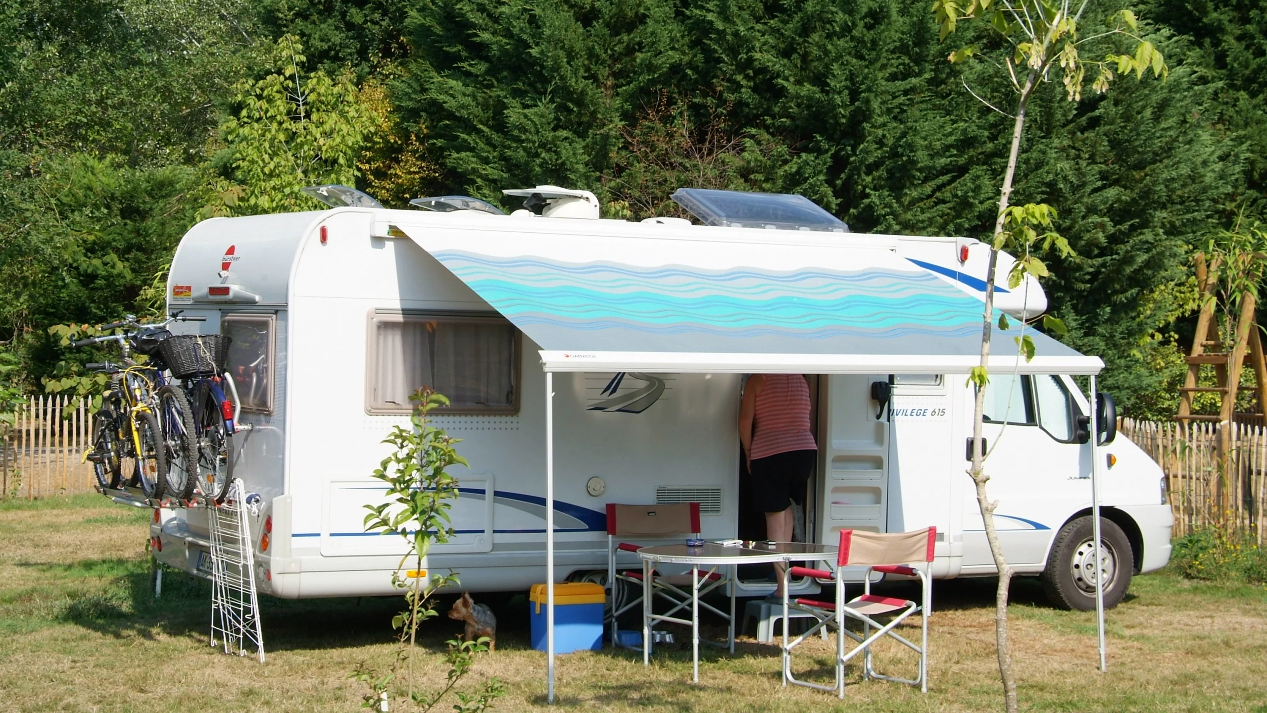 Camping-car avec vélos et auvent dans la nature.