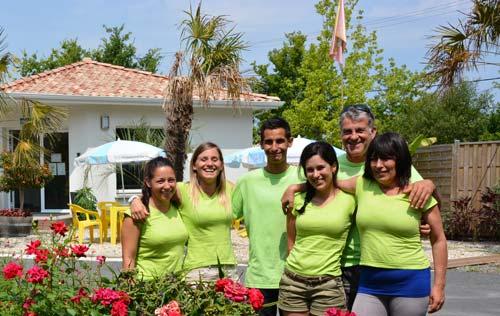 Équipe souriante devant un bâtiment ensoleillé.