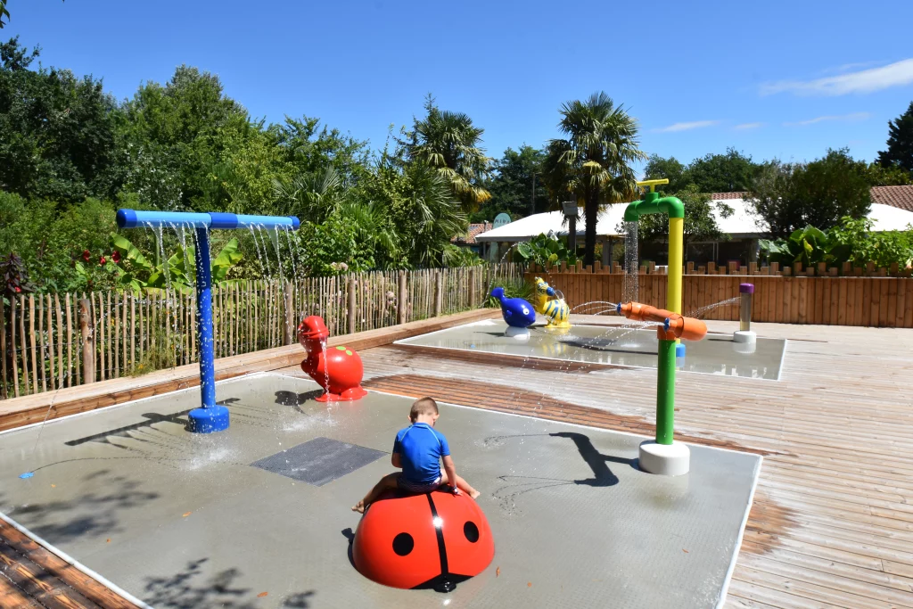 Enfant sur coccinelle dans aire de jeux aquatique.