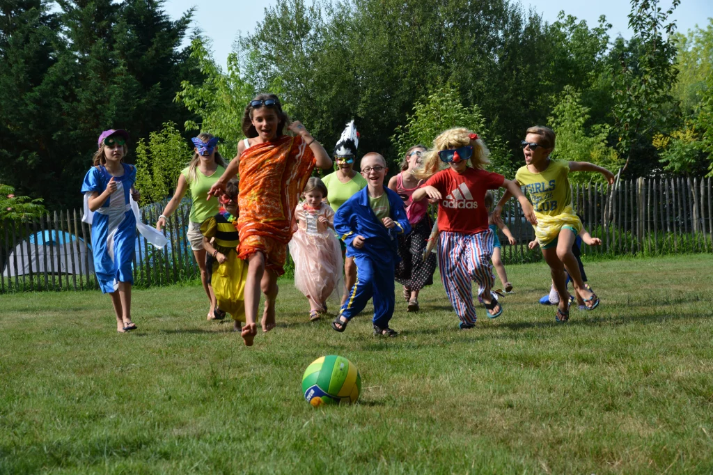 Enfants déguisés jouent au ballon dans le jardin.