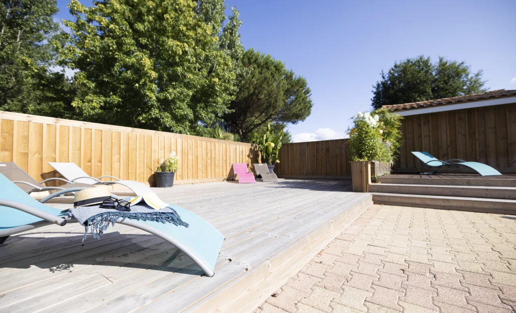 Terrasse en bois avec chaises longues et parasol.