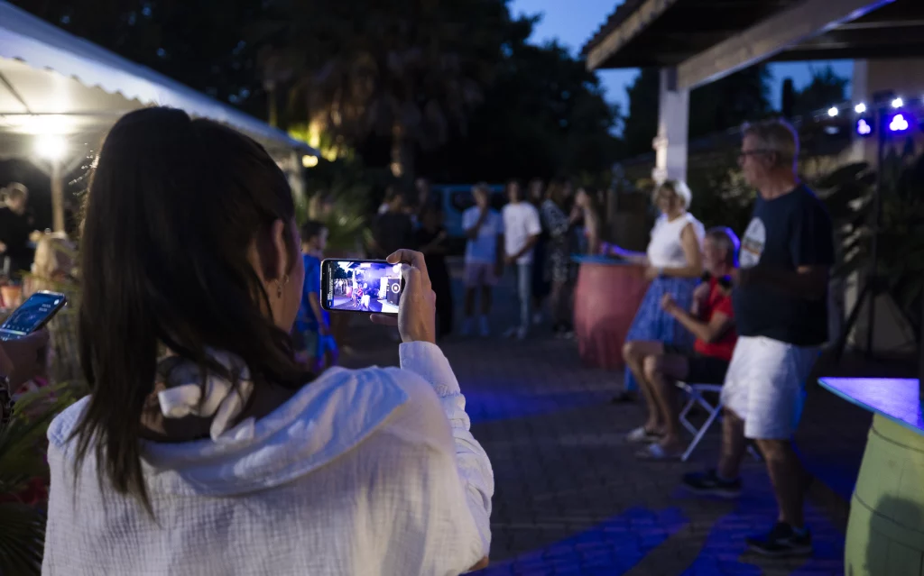 Personne filmant soirée en plein air avec smartphone.