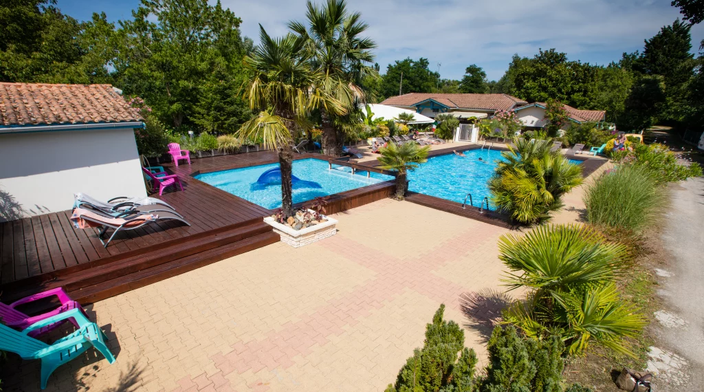 Piscine extérieure entourée de chaises longues colorées.