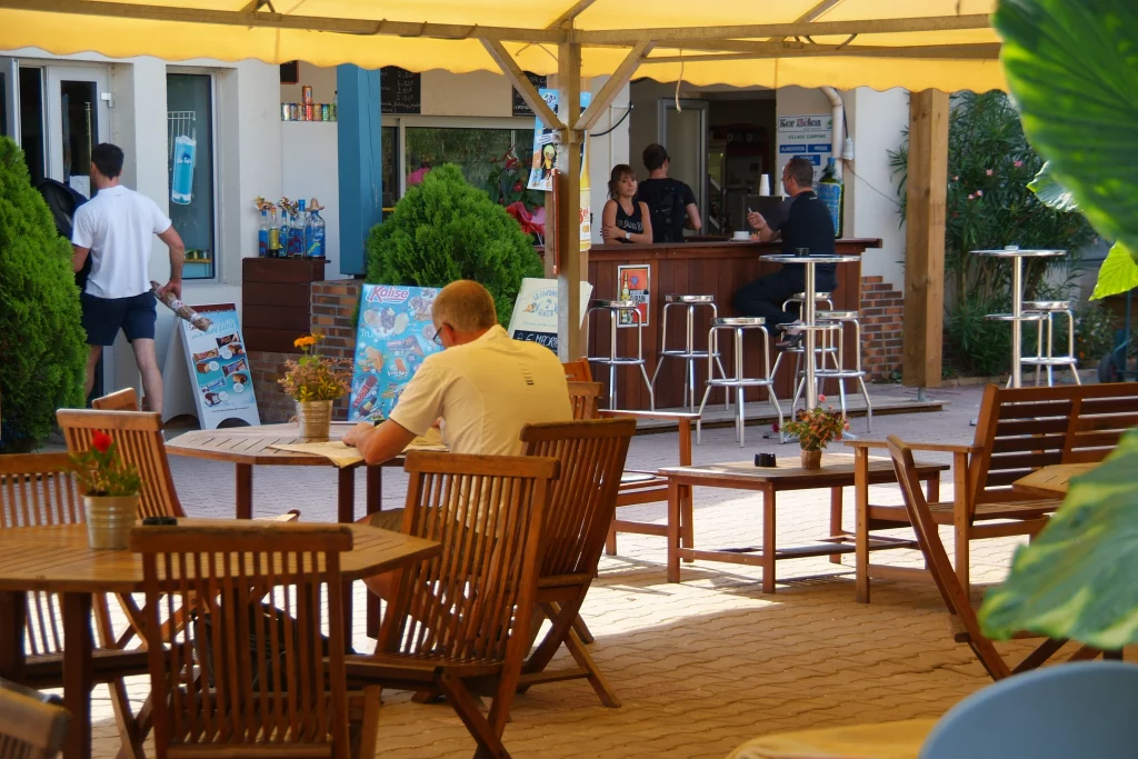 Terrasse de café avec clients sous auvent.