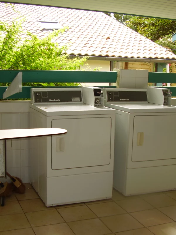 Deux sèche-linges blancs dans une buanderie extérieure.