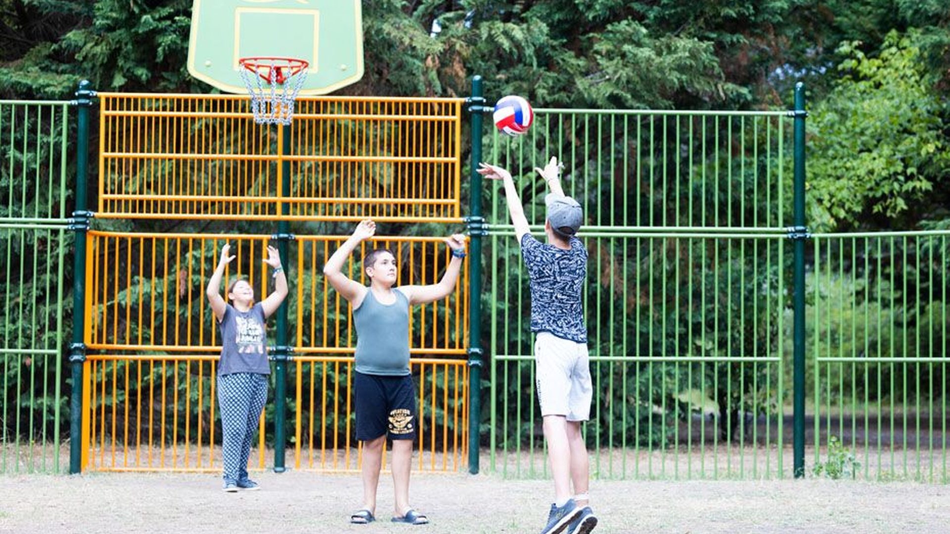 Enfants jouant au basket-ball en extérieur.